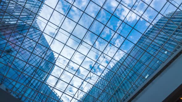 Time lapse of Looking up through the sun roof at office building at clouds and sunshine.