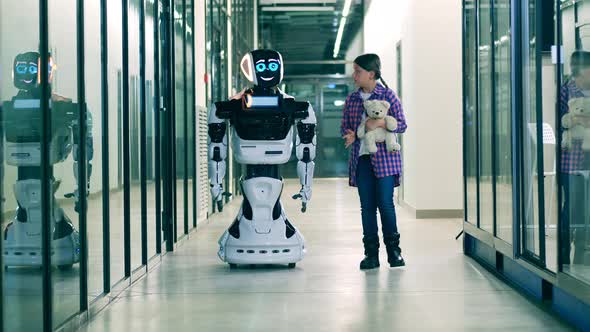 A Girl with a Teddybear Is Talking To a Cyborg