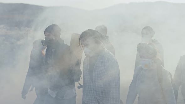 Group of young exhausted people in gas mask going through the toxic smoke