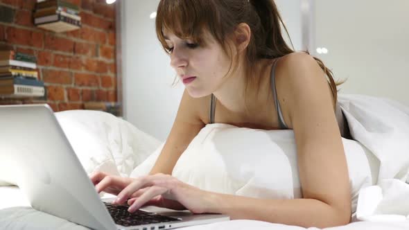 Thinking Pensive Woman in Bed Working on Laptop at Night