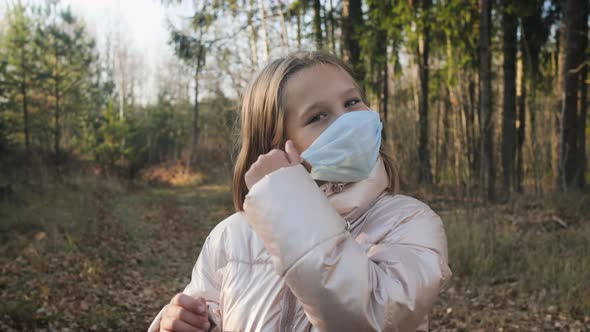 Girl Removing a Medical Mask From Her Face in a Wooded Area