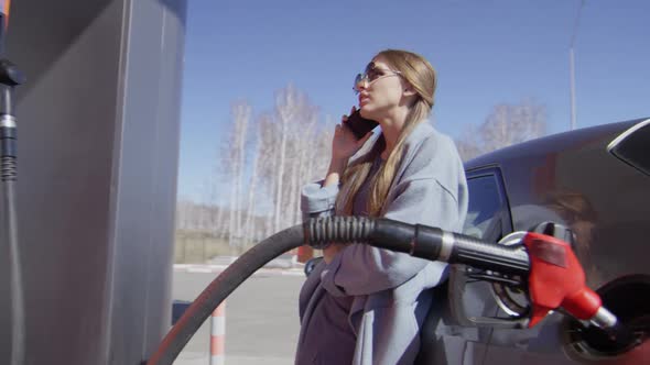 Woman Talking on Phone while Refueling Car