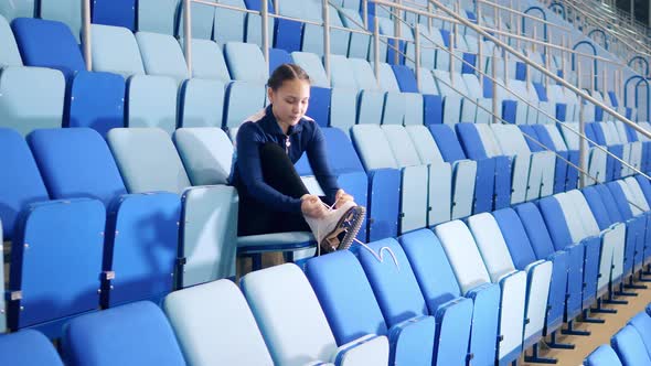 Figure Skater is Lacing Up the Shoes on the Bleachers