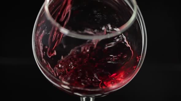 Rose Wine. Red Wine Pour in Wine Glass Over Black Background. Slow Motion