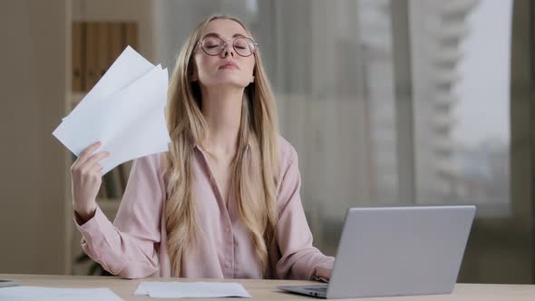 Caucasian Tired Sad Woman Sit at Desk in Office Suffer From Heat Cools Herself with Documents Papers