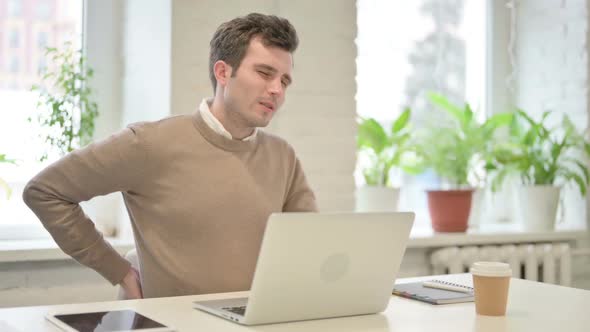 Man Having Back Pain While Using Laptop in Office