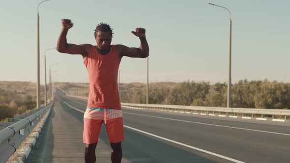 AfricanAmerican Man is Standing on the Road and Warming Up