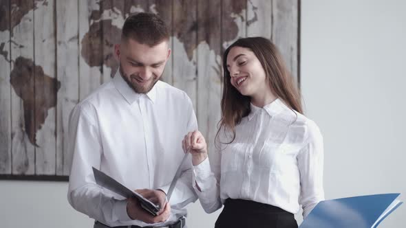 Confident Man and Woman Are Looking Through Documents in the Office