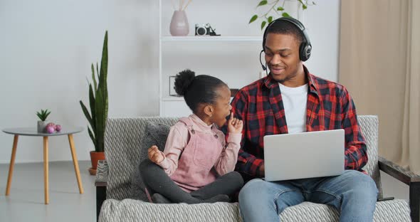 Little Funny Ethnic Girl Afro American Child Sitting with Dad on Sofa Meditates While Father Answers