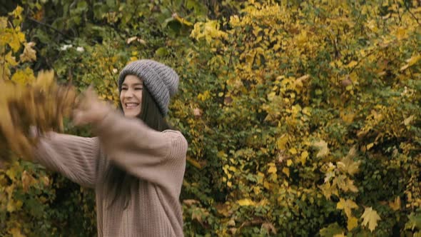 Happy Girl with Smile on Face Throws Autumn Leaves Up in the Park