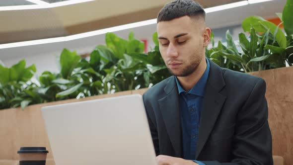 Young Businessman Working on Laptop in Cafe