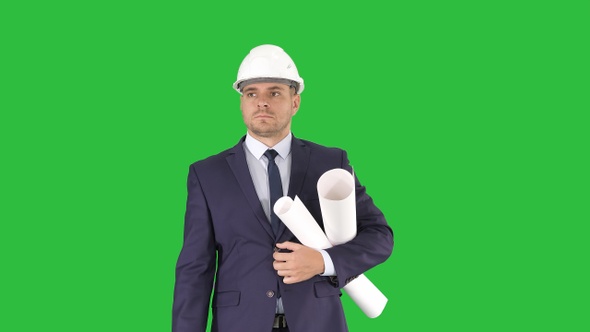 Male architect in a suit and hard hat walking with blueprints