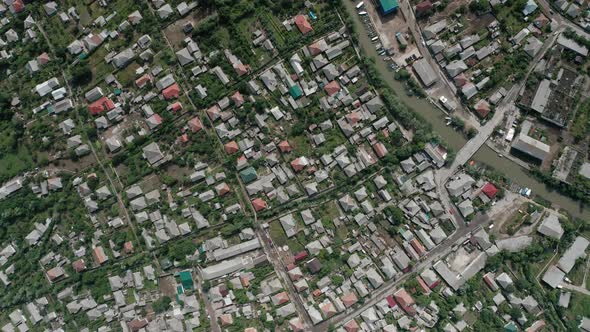 Top View of the Roofs of Houses of a Small Town with a River Bridge Cars Boats