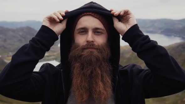 Bearded tourist in hood against picturesque landscape