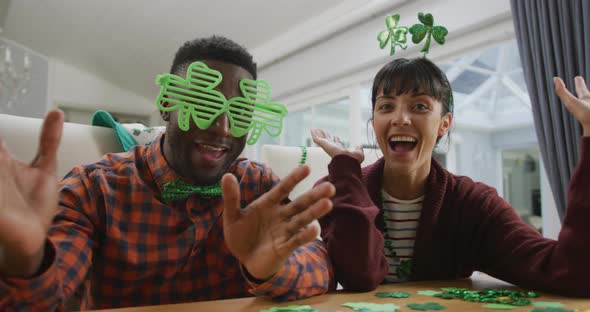 Portrait of happy diverse couple wearing clover shape items and having video call