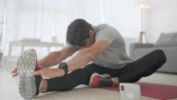 Sporty Caucasian Man Working Out, Doing Cross Fit Sport Exercise on Carped While Watching Fitness