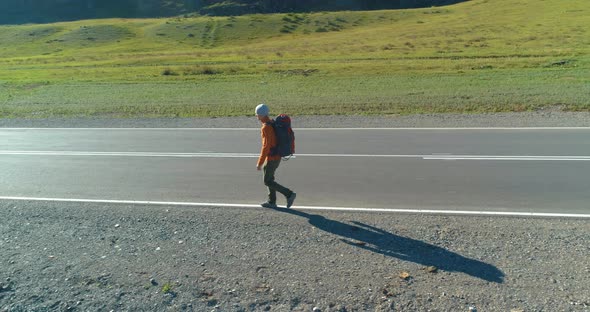 Flight Over Hitchhiker Tourist Walking on Asphalt Road, Huge Rural Valley at Summer Day, Backpack