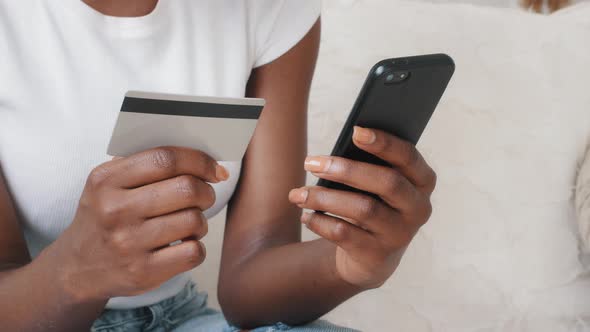 Closeup Young African American Female Shopper Holding Smartphone and Credit Card in Hands Using
