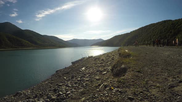 Clear Sunny Day and Sunlit River in Mountains, Group of People Aside Riverbank