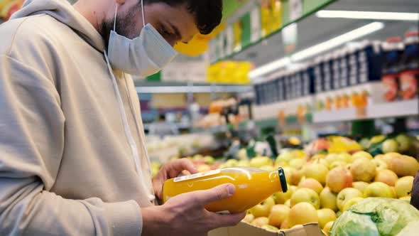 Masked Man Reading Product Information in Glass Bottle While Shopping at Supermarket