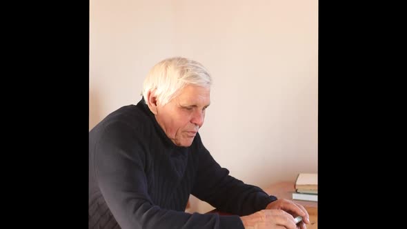 Smiling Old Man Using Smartphone While Sitting on Couch