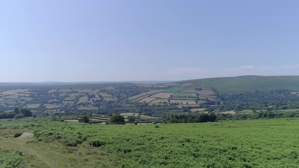 Wide aerial tracking upwards fast to reveal a vast horizon of fields with moorland in the foreground