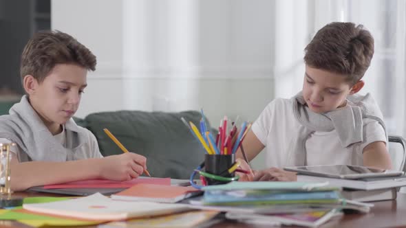 Portrait of Caucasian Schoolboys Sitting at the Table and Doing Homework.