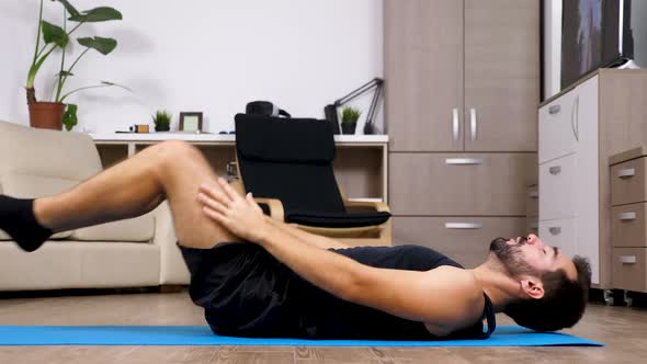 Young Fit Man on the Floor in His Living Room Does Different Yoga Poses