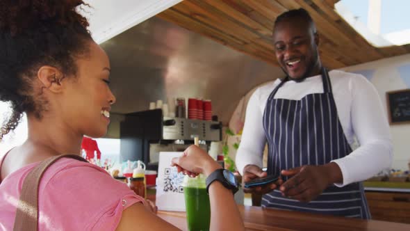 African american woman making payment from her smartwatch at the food truck