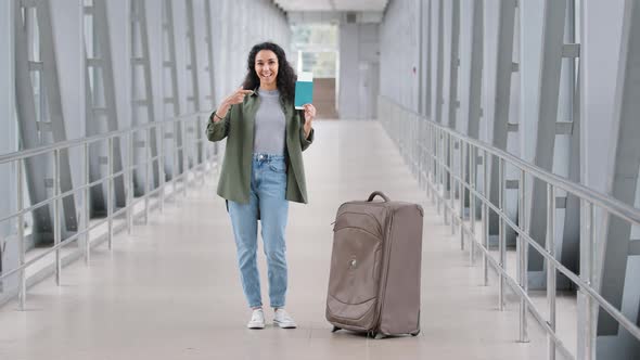 Happy Contented Hispanic Young Girl Traveler Tourist Woman Standing at Airport with Suitcase Shows