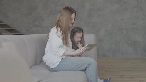 Portrait Pretty Smilling Young Mother and Her Adorable Cute Little Daughter Are Using a Tablet