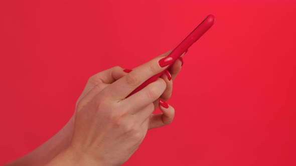 Female Hands Texting on Her Smartphone on Red Studio Background