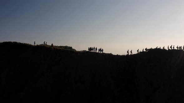 Hikers at the summit of Mout Batur volcano in Bali Indonesia walk along the crater ridge, Aerial orb