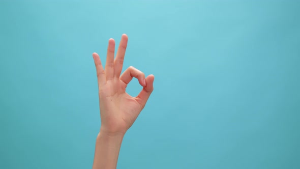 Close up of woman hand showing ok sign okay gesture on the blue background