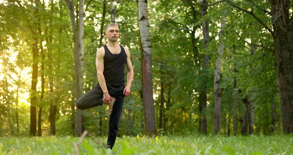 Young Man Practicing Yoga Lesson Inside a Park in the Morning