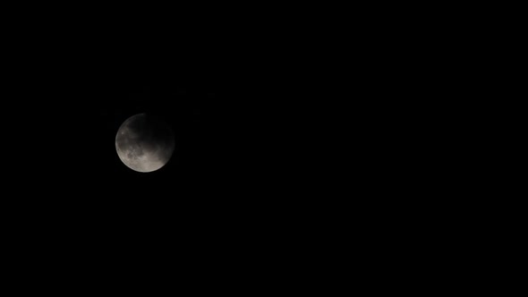 a full moon with some dark clouds passing by