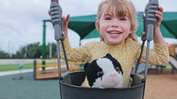 Beautiful Little Girl Smiling at Camera While at Toddler Swing