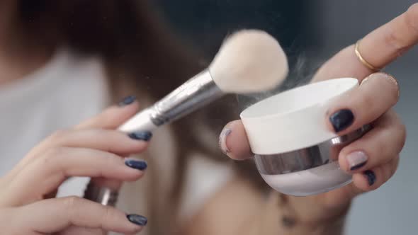Makeup Artist Holding Cosmetics and Brush in Beauty Studio