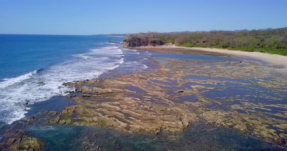 Aerial drone view of the beach, rocks and tide pools in Playa Palada, Guiones, Nosara, Costa Rica.