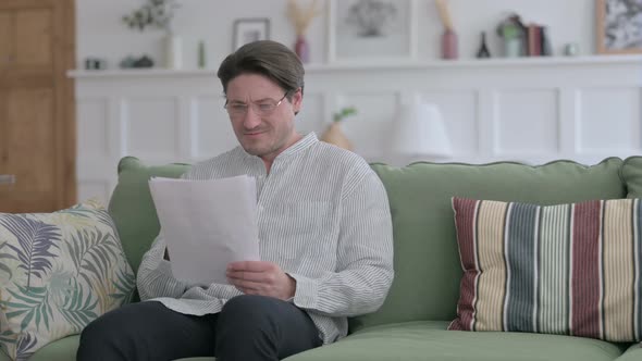 Man Reacting to Loss on Documents, Sofa