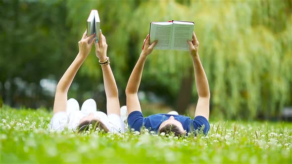 Relaxed Young Couple Reading Books While Lying on Grass