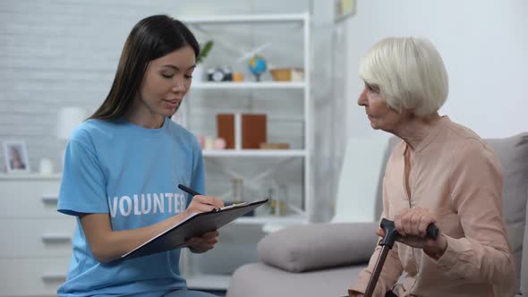 Young Activist Making List Listening to Aged Lady Walking Stick, Nursing Home