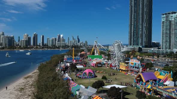 Aerial view of a colourful carnival situated by the sea with a city skyline in the background