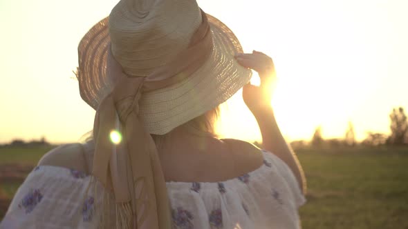 A Beautiful Rural Woman Walks Through the Field Against the Backdrop of the Sunset