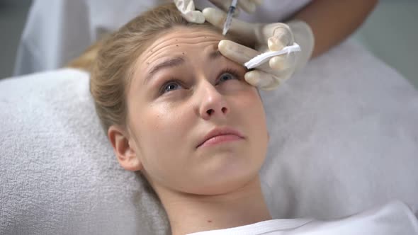 Cosmetologist Making Injection of Botox to Young Woman, Wrinkle Smoothing
