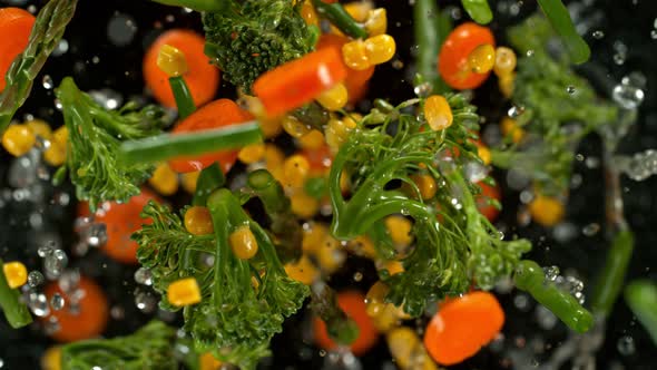 Super Slow Motion Shot of Flying Cuts of Colorful Vegetables and Water Drops on Black at 1000Fps