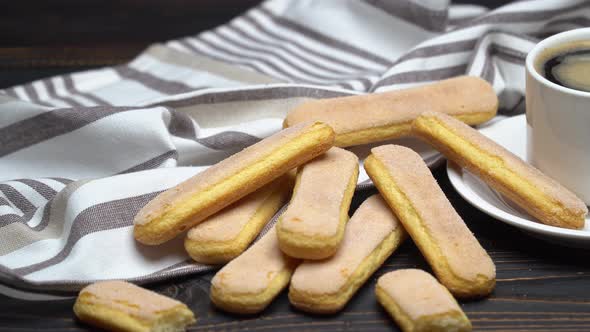 Italian Savoiardi Ladyfingers Biscuits and Cup of Coffee on Wooden Background