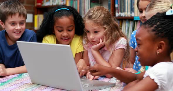 Pupils using the laptop together in the library