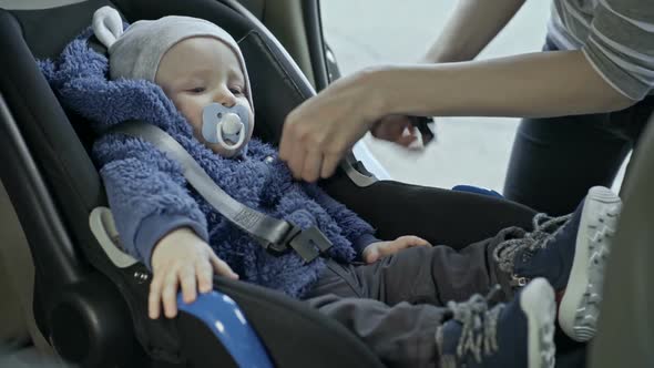 Mother Placing Baby into Car Seat