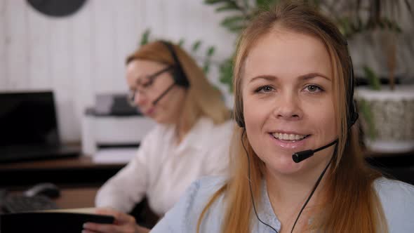 Closeup Portrait of a Smiling Woman with a Headset in a Call Center Office